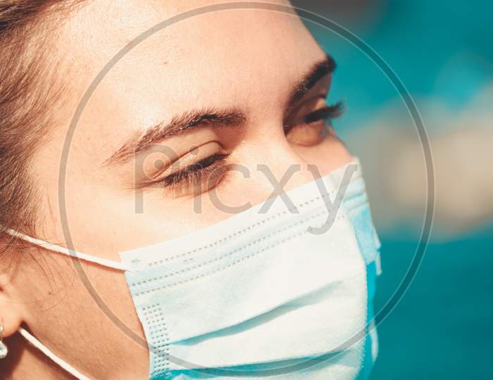 Super Close Up Of A Young Woman Wearing A Surgical Mask For Protection While Smiling And Looking Away