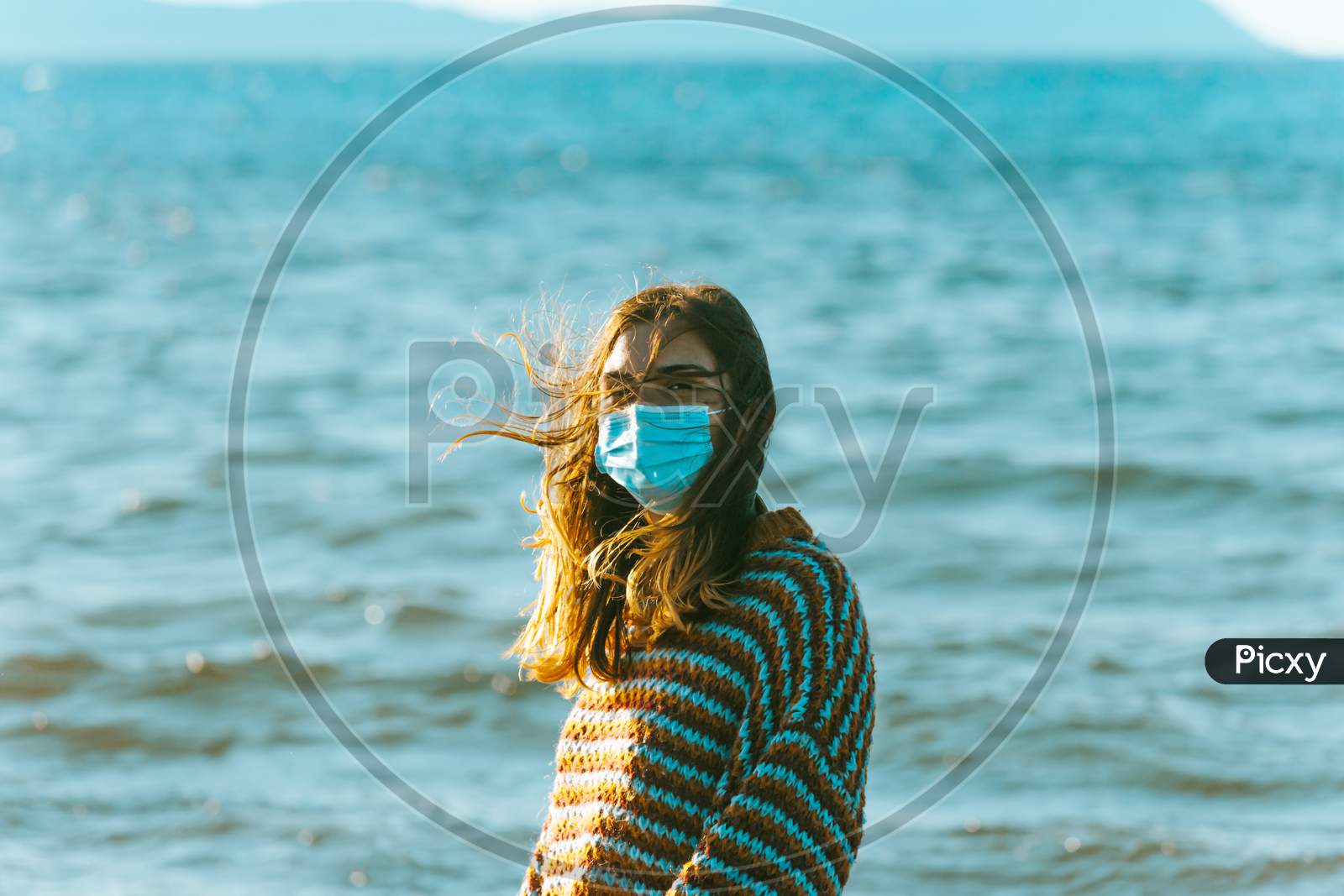 Young Woman On A Jersey On The Beach Using A Surgical Mask On Moody Tones