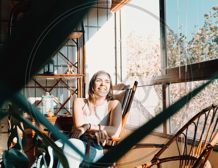 Young Woman On Vintage Clothes Sitting Near A Window With A Bright Day And Smiling With Copy Space And Colorful