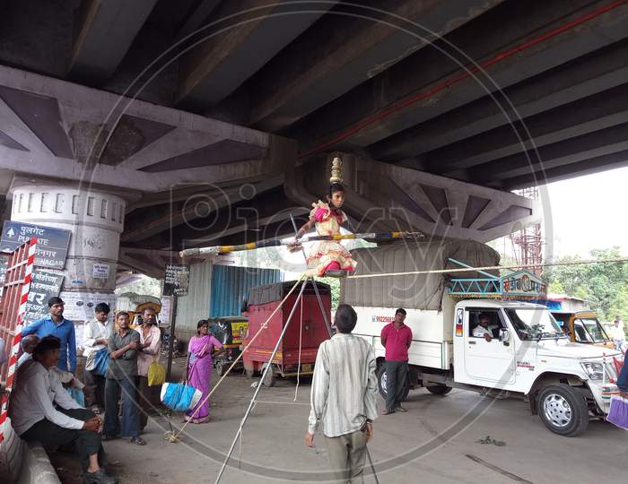 Balancing on rope by poor little girl on street with people around