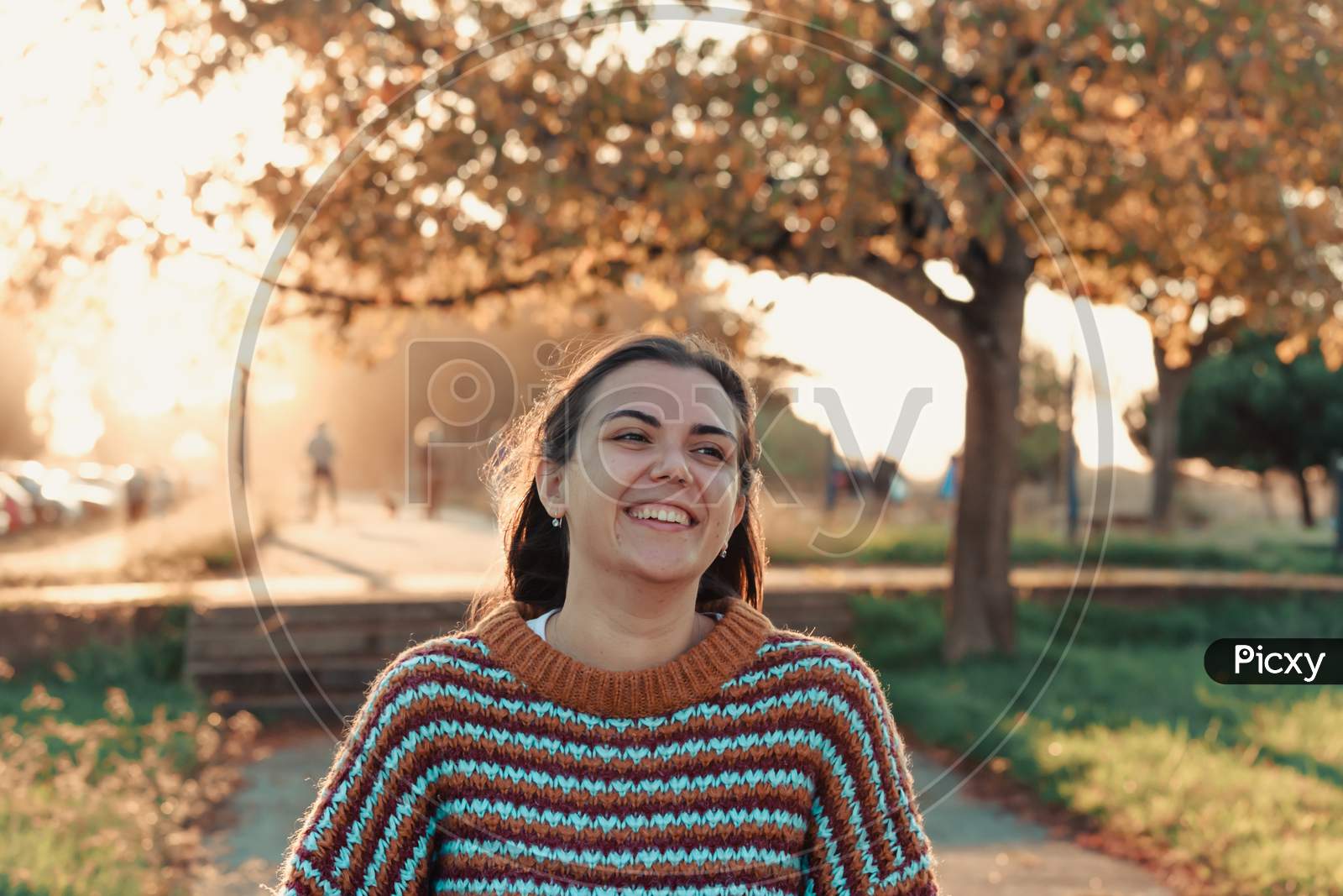 Young Woman Smiling During A Colorful Sunset In A National Park While Wearing An Autumnal Sweater