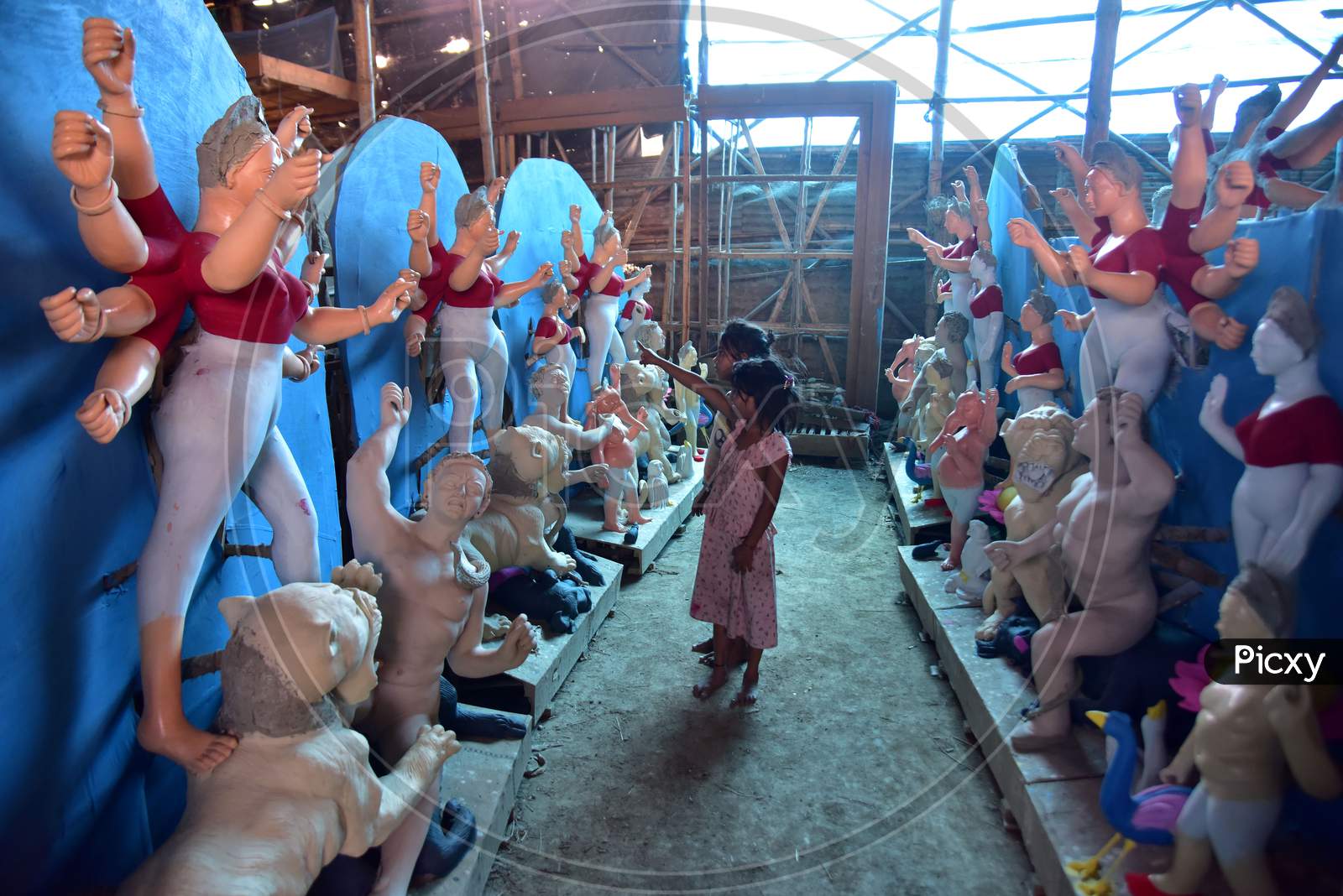 Children look at an incomplete  idol of the Goddess Durga ahead of the upcoming 'Durga Puja' festival in Guwahati,on Oct 13,2020.