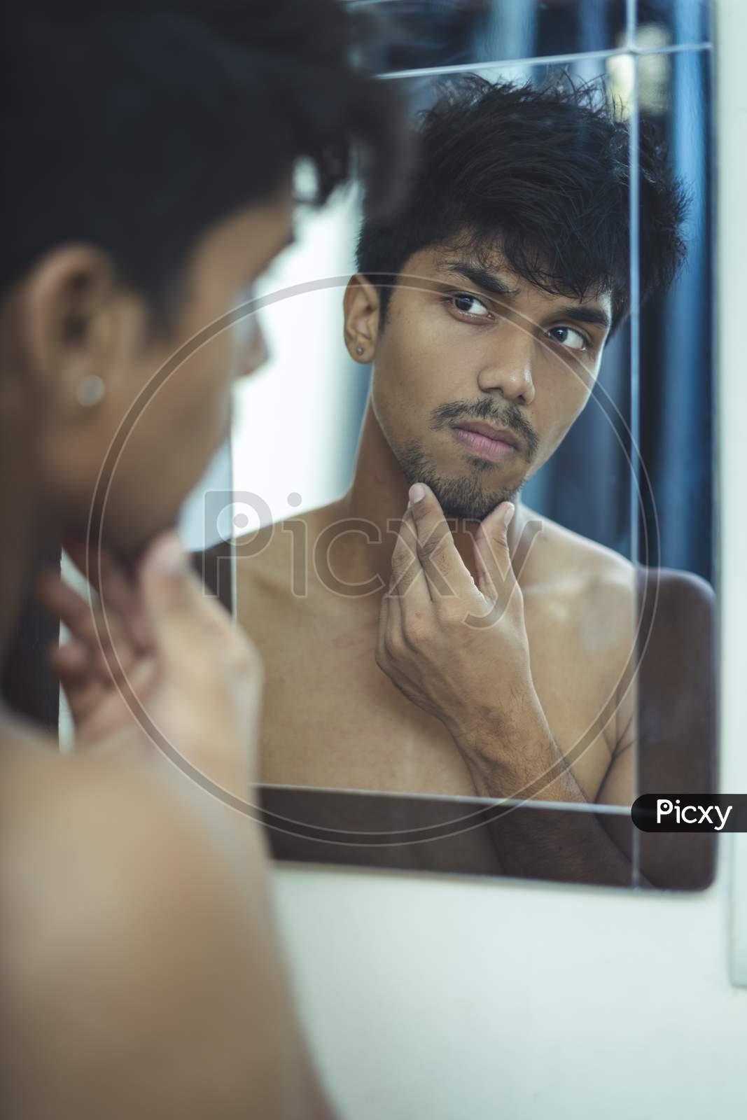 Handsome Caucasian Man Looking At Himself At The Mirror Bathroom