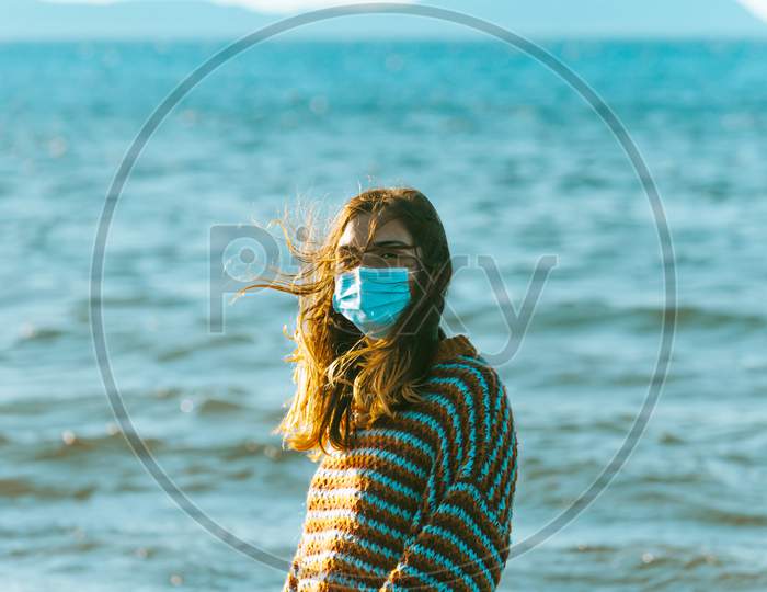 Young Woman On A Jersey On The Beach Using A Surgical Mask On Moody Tones