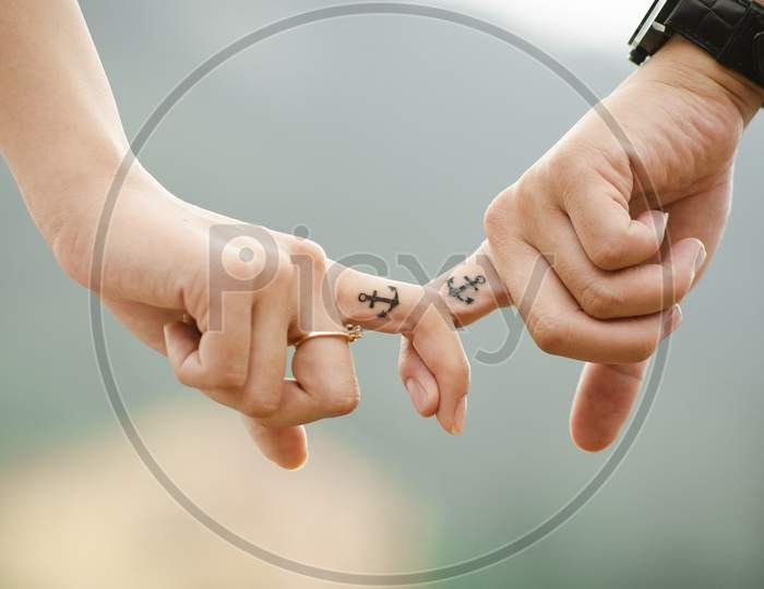 Image of two couple holding their finger.