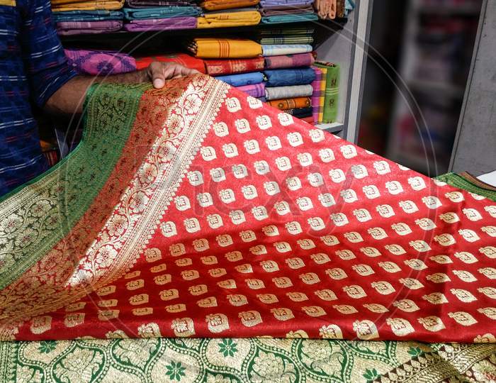 A seller displaying Indian sari in a clothing store