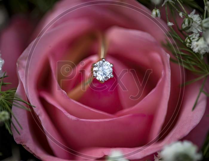a wedding ring put inside a rose flower