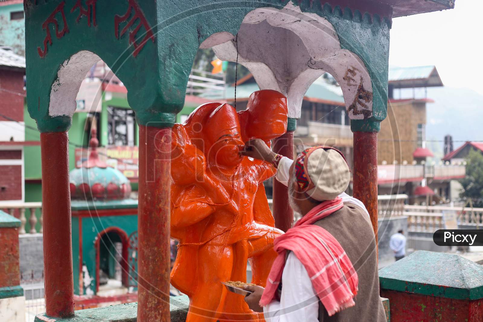 a man giving food to a hanuman idol