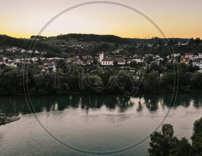 Aerial View Over Aare River, To The Church And Residential Area Of Umiken And Riniken, Switzerland At Sunset.