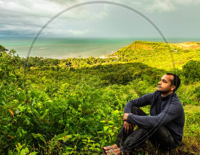 Man Sitting At Hilltop With Landscape Serene View And Dense Green Forests