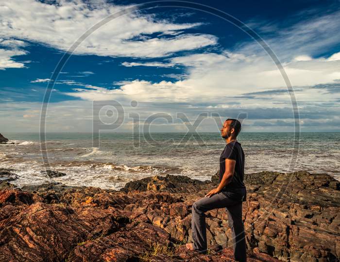Man At Rocky Sea Shore In The Morning From Flat Angle