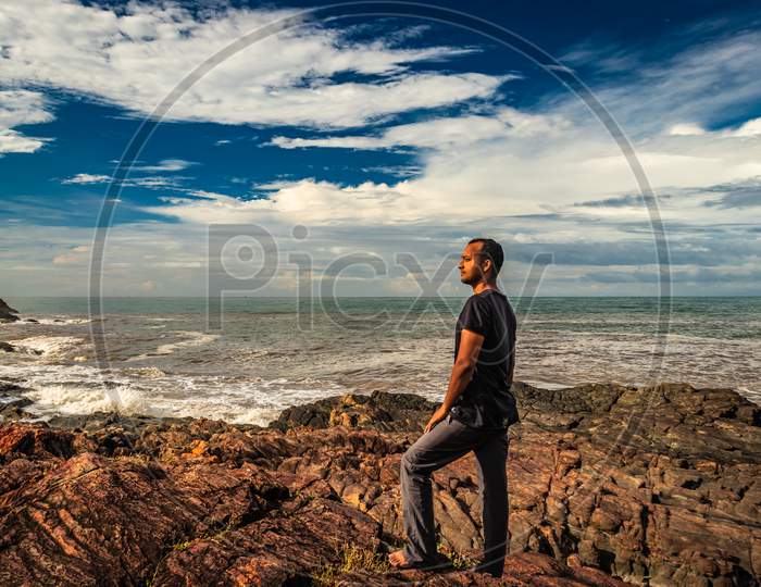 Man At Rocky Sea Shore In The Morning From Flat Angle