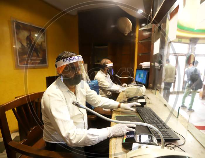 Workers wear facemasks and face shields  inside a theatre during a sanitisation work ahead of the scheduled reopening of cinema theatres on October 15 as the Covid-19 coronavirus imposed lockdown eases further in New Delhi on October 13, 2020.