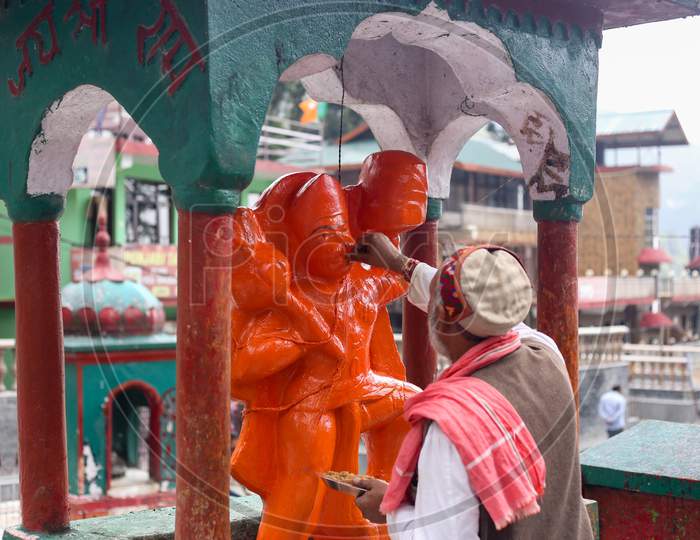 a man giving food to a hanuman idol