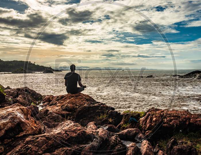 Man Meditating At Rock At Sea Shore At Morning From Flat Angle