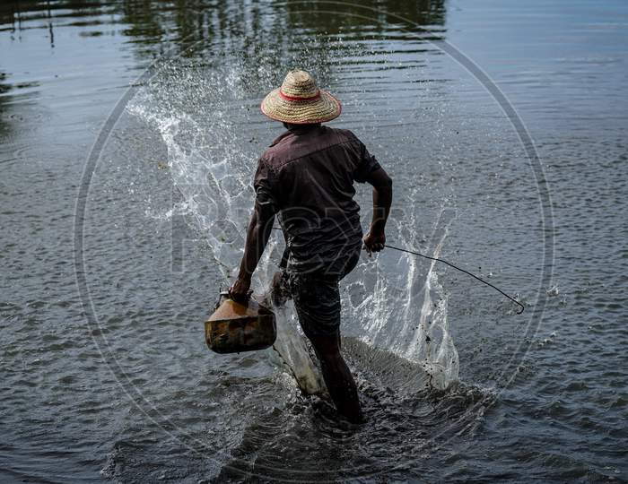 A fisherman searching for crabs in the water.