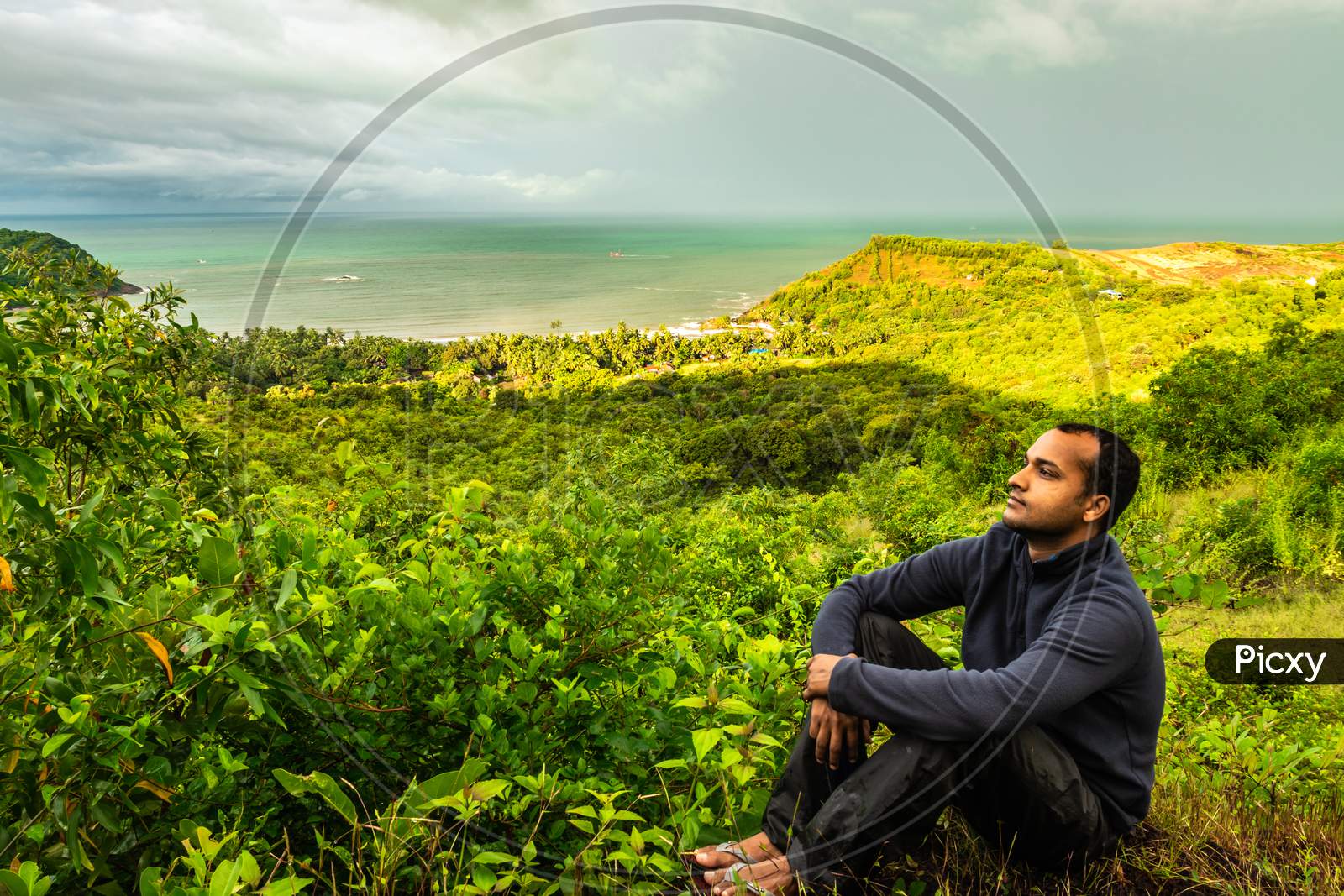 Man Sitting At Hilltop With Landscape Serene View And Dense Green Forests