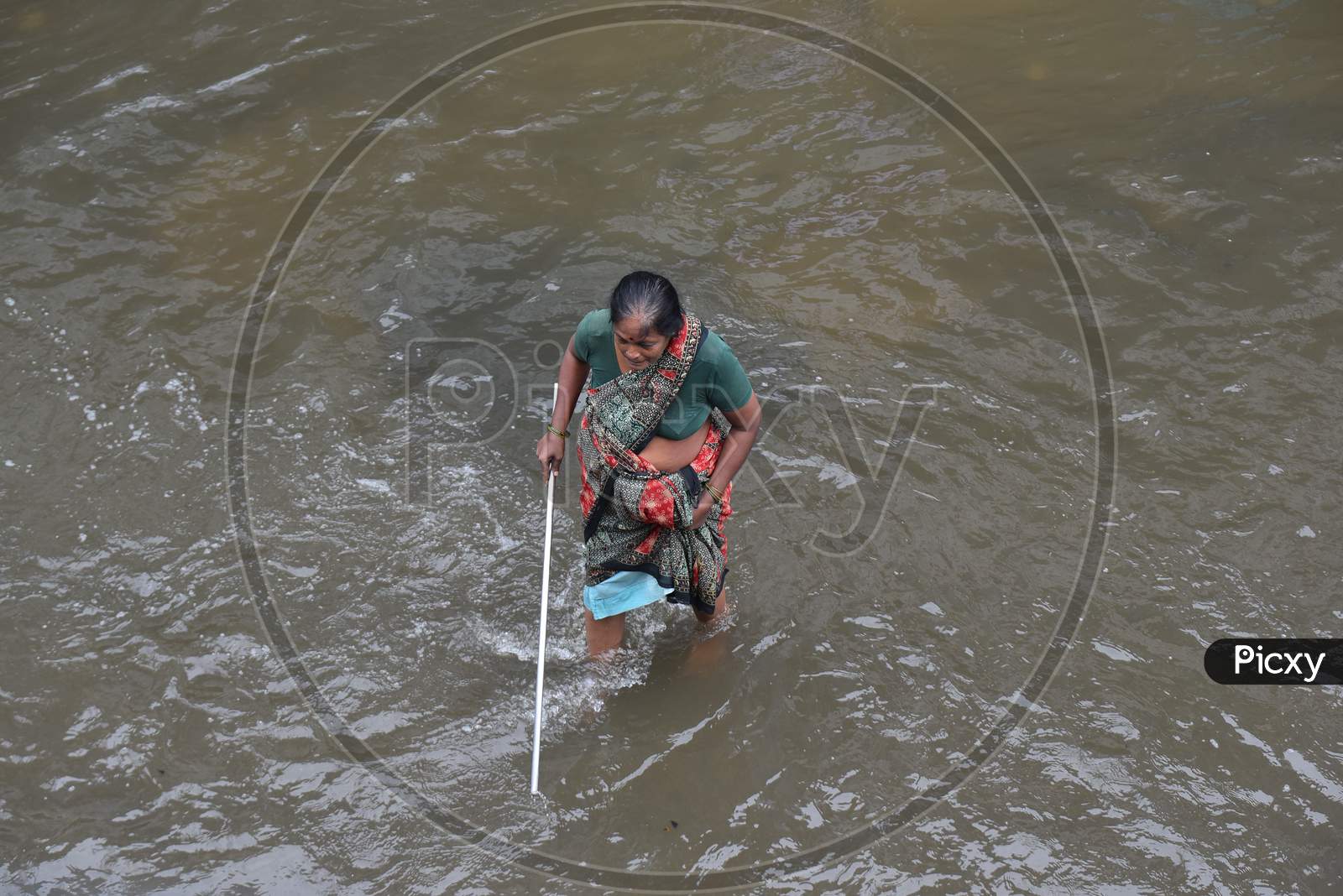an elderly woman tries to walk with a stick on a flood affected road in Tolichowki, Hyderabad on October 14, 2020.