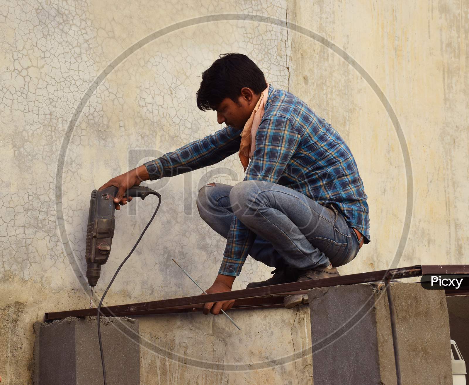 Indian construction worker drilling