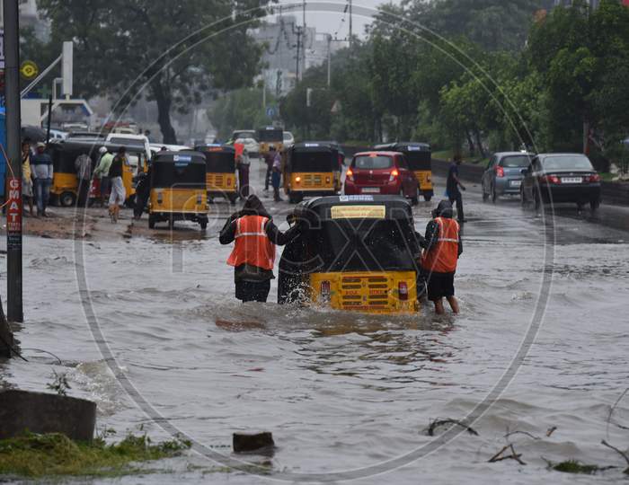 GHMC workers and passers by try to push an auto that got stuck in the rain water in Tolichowki,Hyderabad on October 14, 2020.