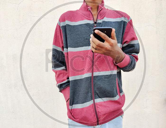 Young Man Wearing Warm Clothes Using Smart Phone. Isolated On White Background. Winter Portrait