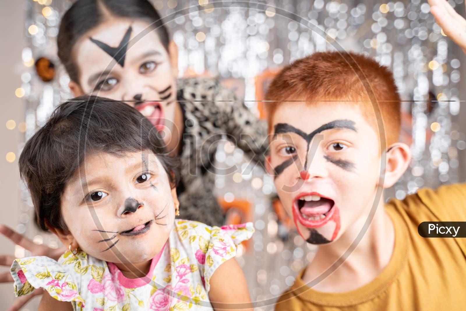 Group Of Kids In Halloween Costumes Gesticulating And Making Scary Or Spooky Faces On Decorated Background By Looking Into Camera.