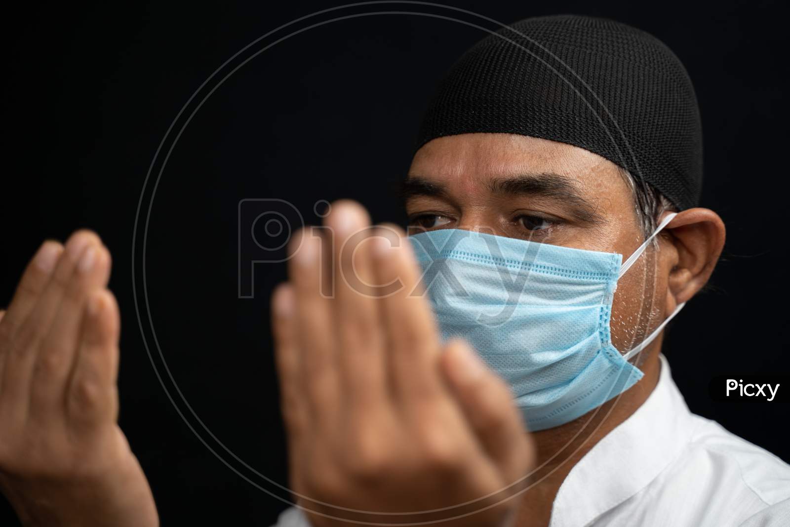 Muslim Man In Medical Mask Preforming Salah Or Prayer By Closing Eyes.