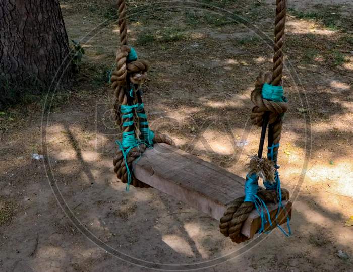 A wooden swing in the park.