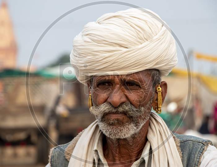An old man dressed traditionally and carrying a turban in Pushkar Fair