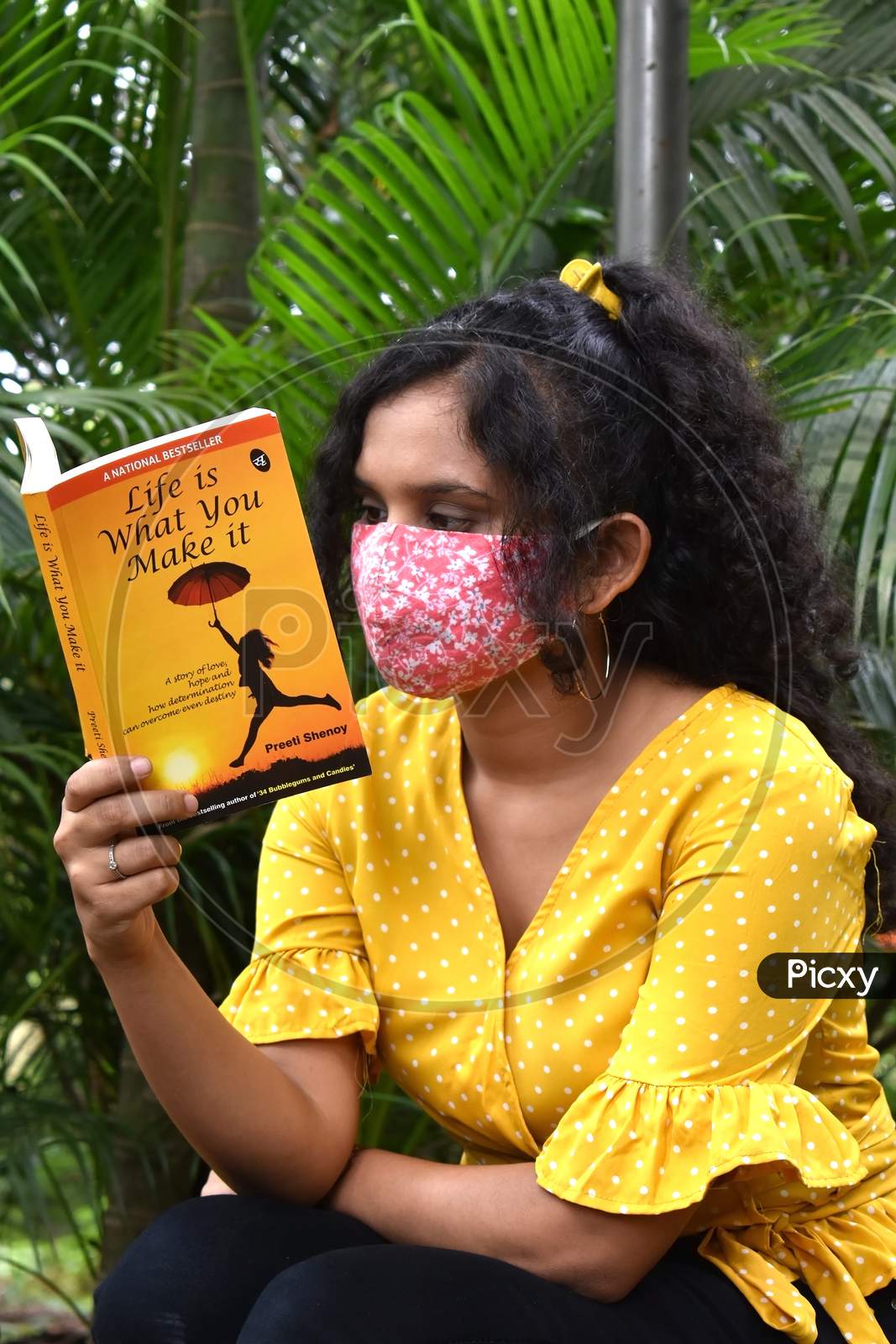 Girl in mask reading book in garden