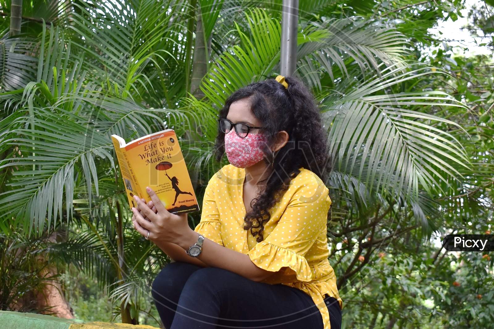 Girl in mask reading book in garden