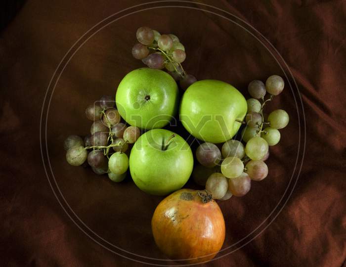 Image Of Tasty Green Apple,Pomegranate And Grape On Fabric.