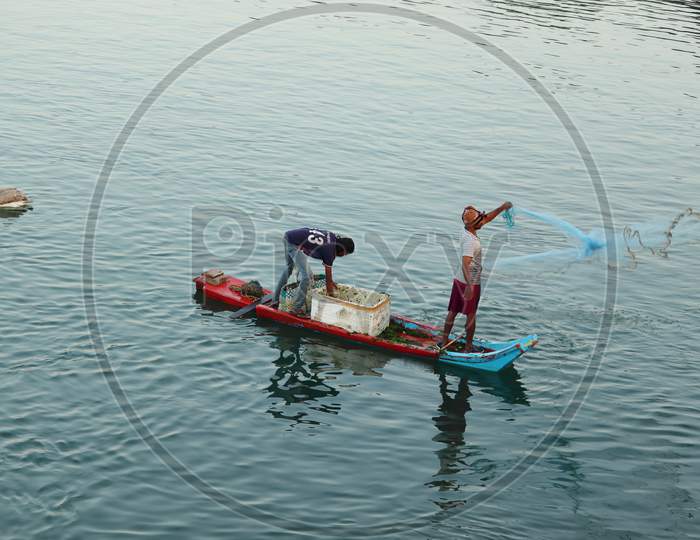 The Fisherman Rode A Boat Made Of Wood And Threw The Net In The Morning To Catch The Fish From The Lake.