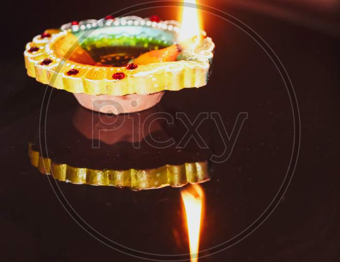 A glowing diya with its reflection in the mirror for diwali celebration