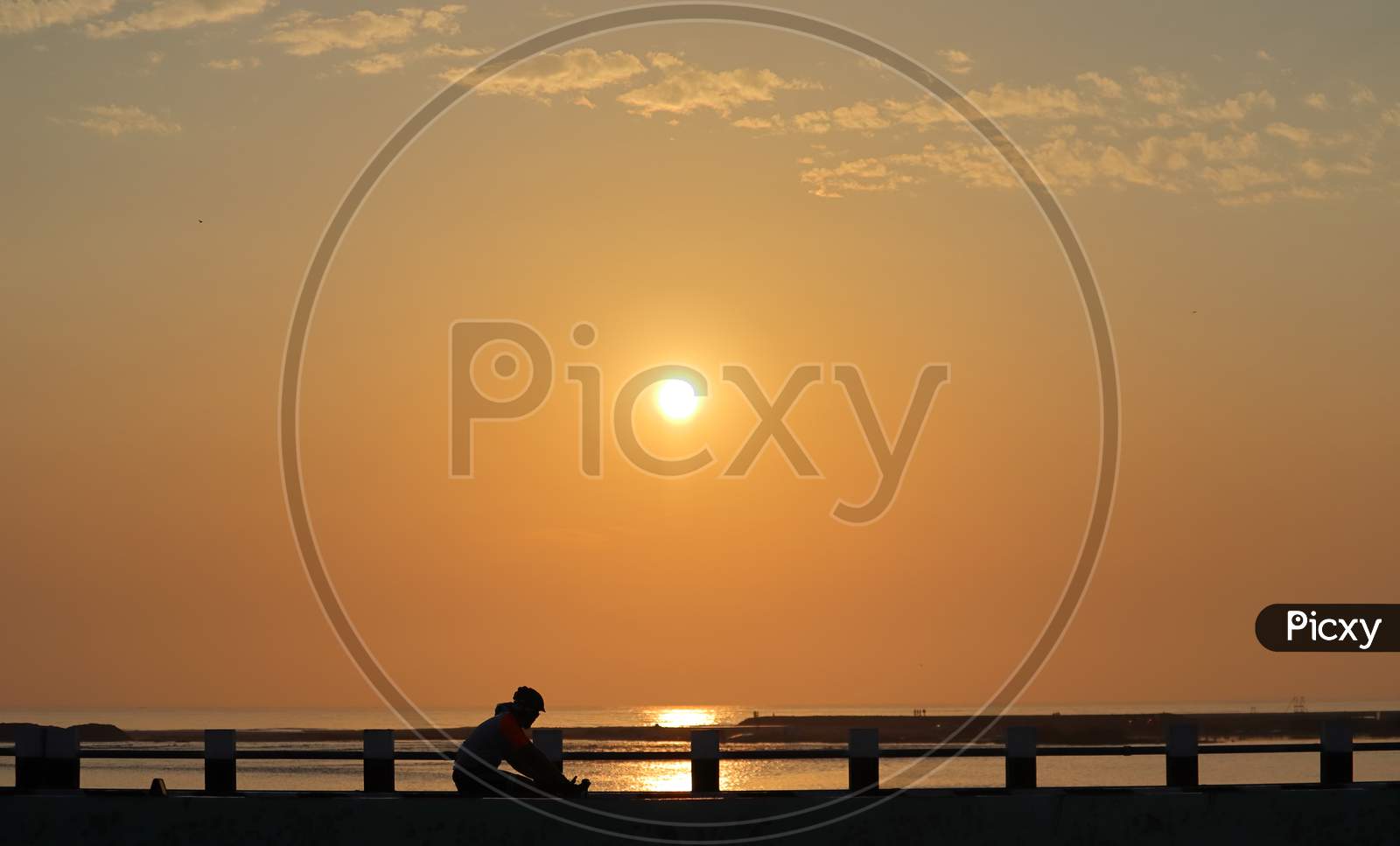 A Silhouette Sport Man Walks The Cycle From The Bridge Over The Seashore In The Morning