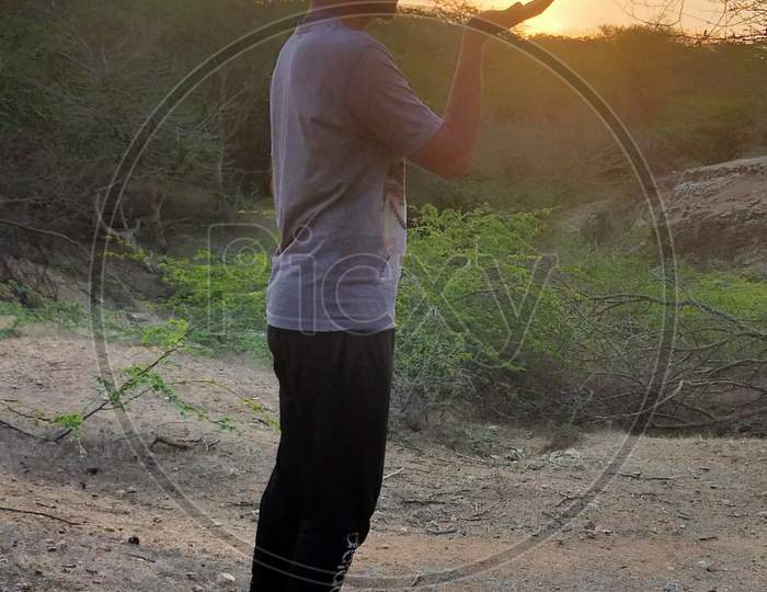 Man /Boy facing the Sunset in Aravali hills in forest