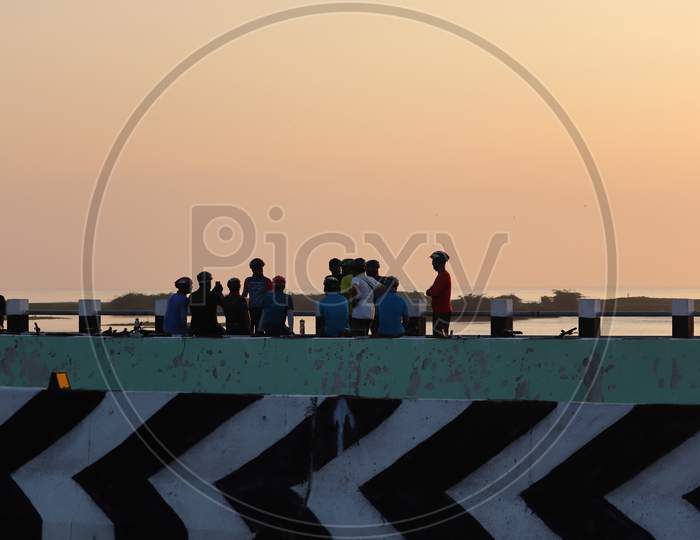 A Group Silhouette Sport Men Gather Atop A Bridge Near The Seaside In The Morning While Doing Selfie Photography