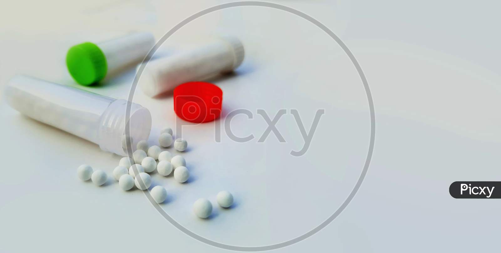 Homeopathic Pills Or Medicines Outside Opened Bottle In White Background