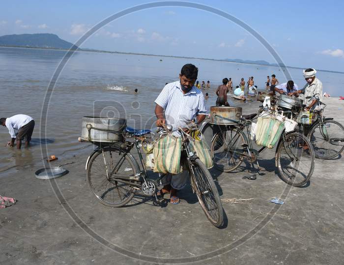 fish vendor cleans his bicycle and basket after selling his catch on the banks of the river Brahmaputra in Guwahati,india on oct 18,2020
