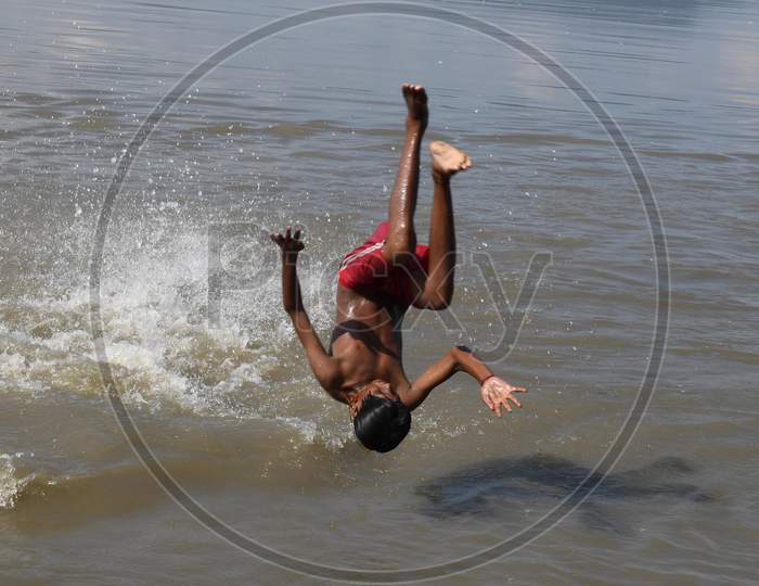 A boy jumps in the Brahmaputra river during a hot day in Guwahati, India on Oct 18, 2020