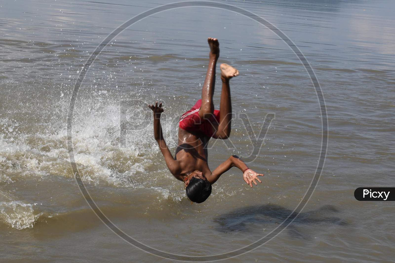A boy jumps in the Brahmaputra river during a hot day in Guwahati, India on Oct 18, 2020