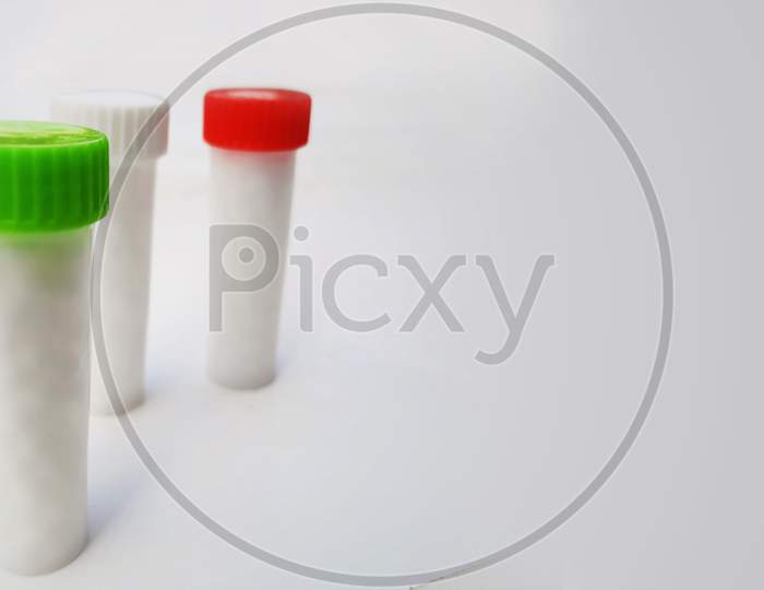 White Homeopathic Pills In Small Bottles Isolated In White Background