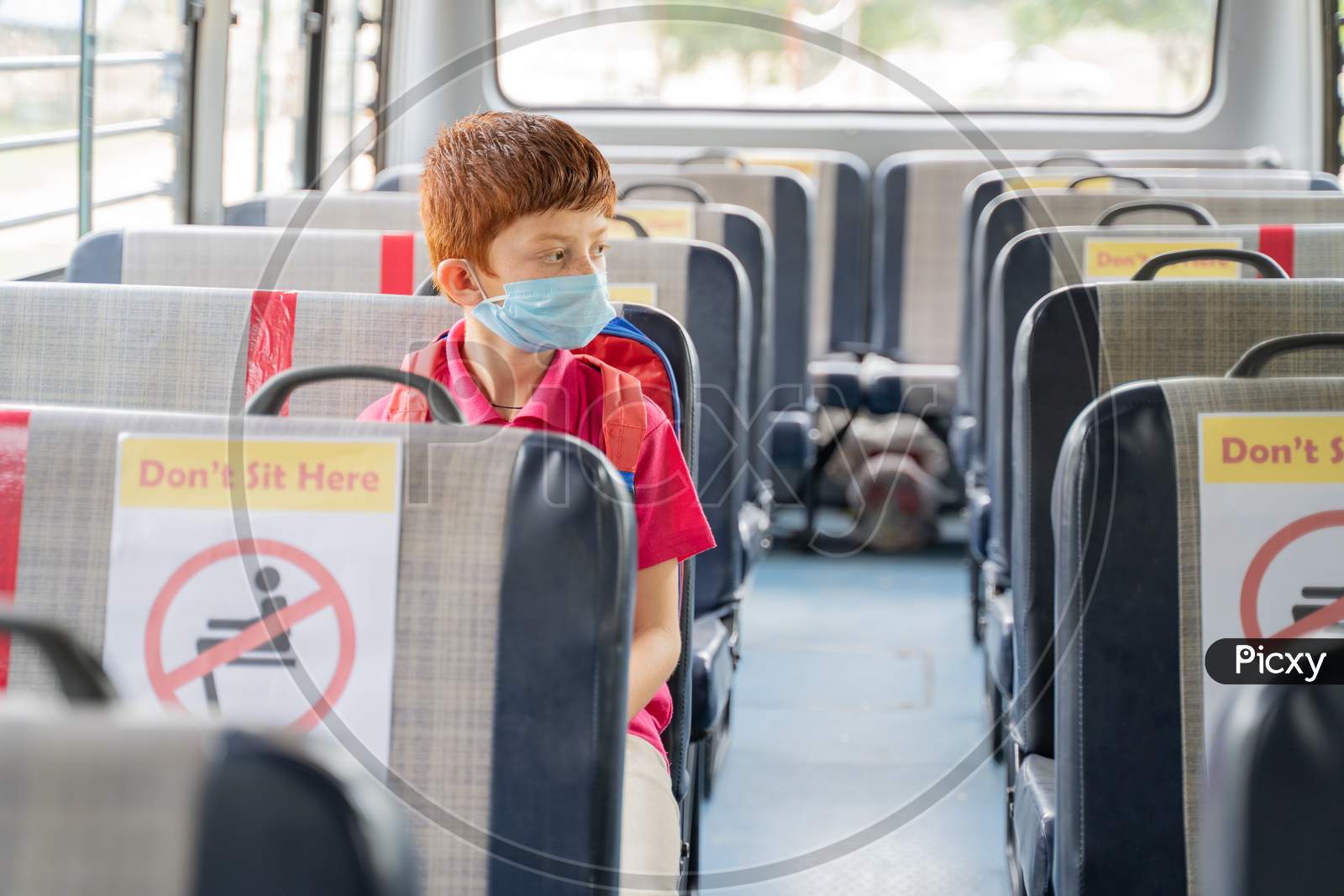 Kid Medical Mask Sitting Inside School Bus While Maintaining Social Distance Due To Coronavirus Or Covid-19 Pandemic - Concept Of School Reopen Or Back To School