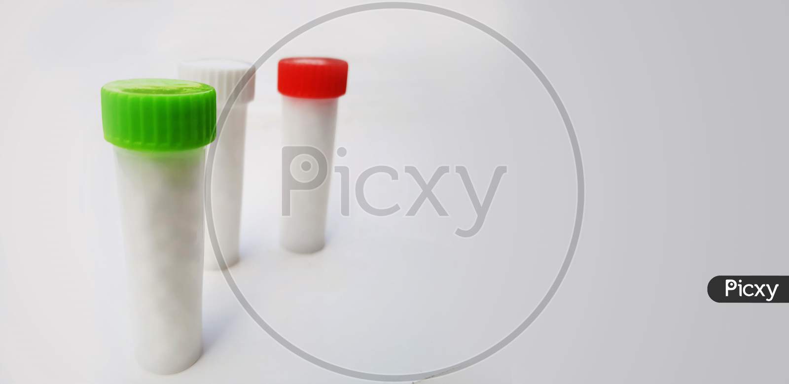 White Homeopathic Pills In Small Bottles Isolated In White Background