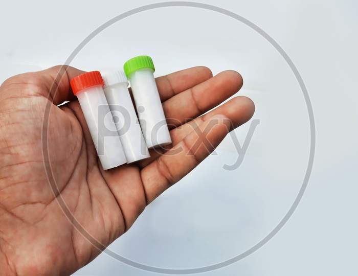 Homeopathic Pills In Small Bottles Hold In Hands In White Background