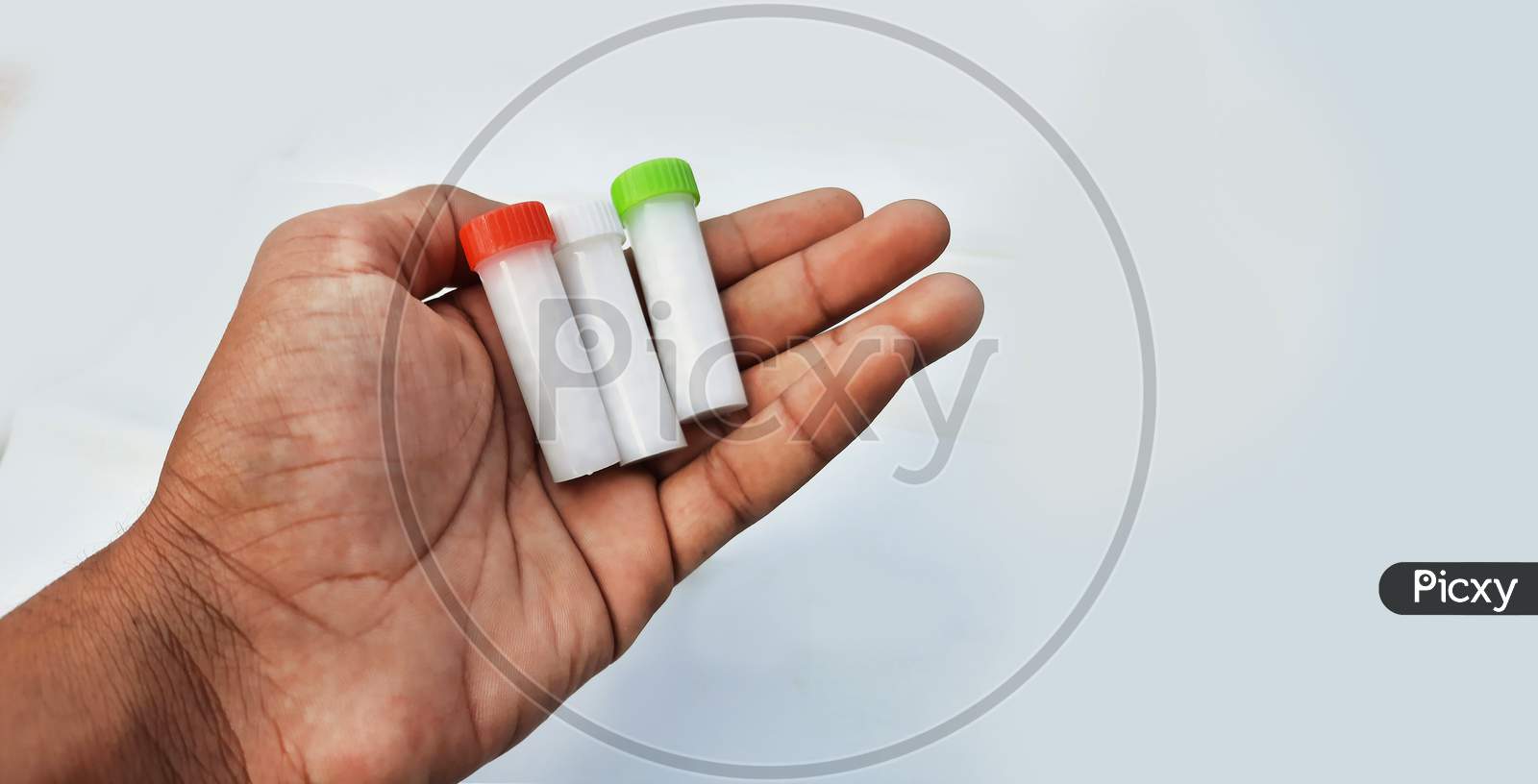 Homeopathic Pills In Small Bottles Hold In Hands In White Background