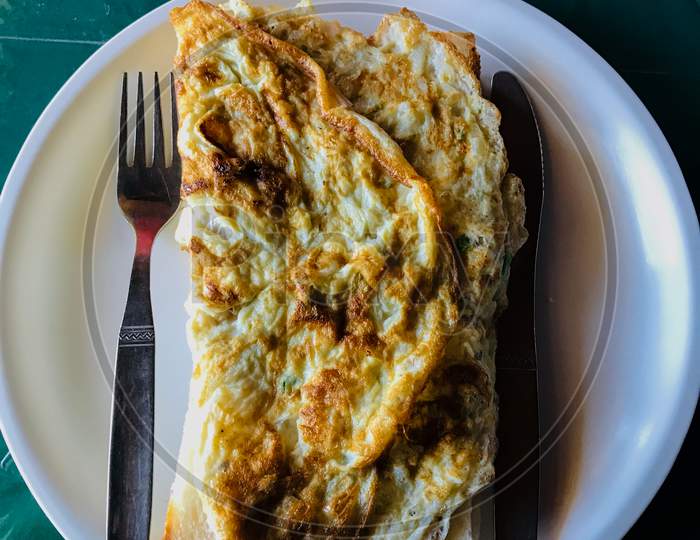 Omelette on a plate with cutlery - Morning breakfast