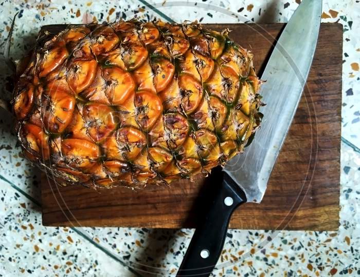 Healthy juicy pineapple on chopping board with a sharp knife