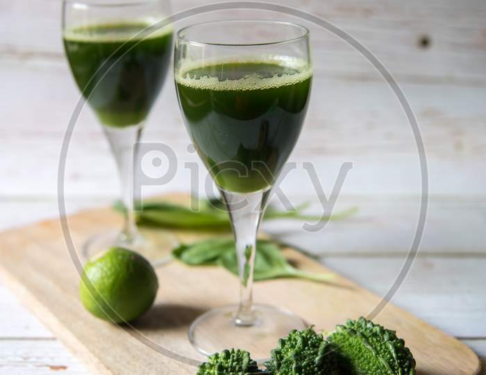 Bitter gourd juice in a wine glass along with condiments