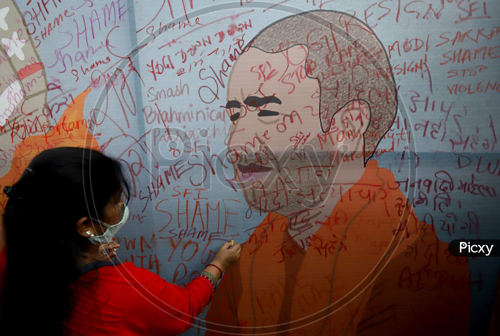 A demonstrator uses a lipstick to write on a billboard during a protest after the death of a rape victim, in New Delhi, India, October 2, 2020.